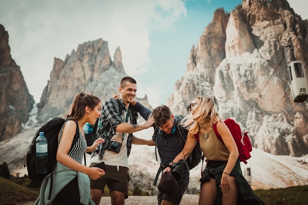 Group of hikers laughing together on a trail below jagged mountain peaks